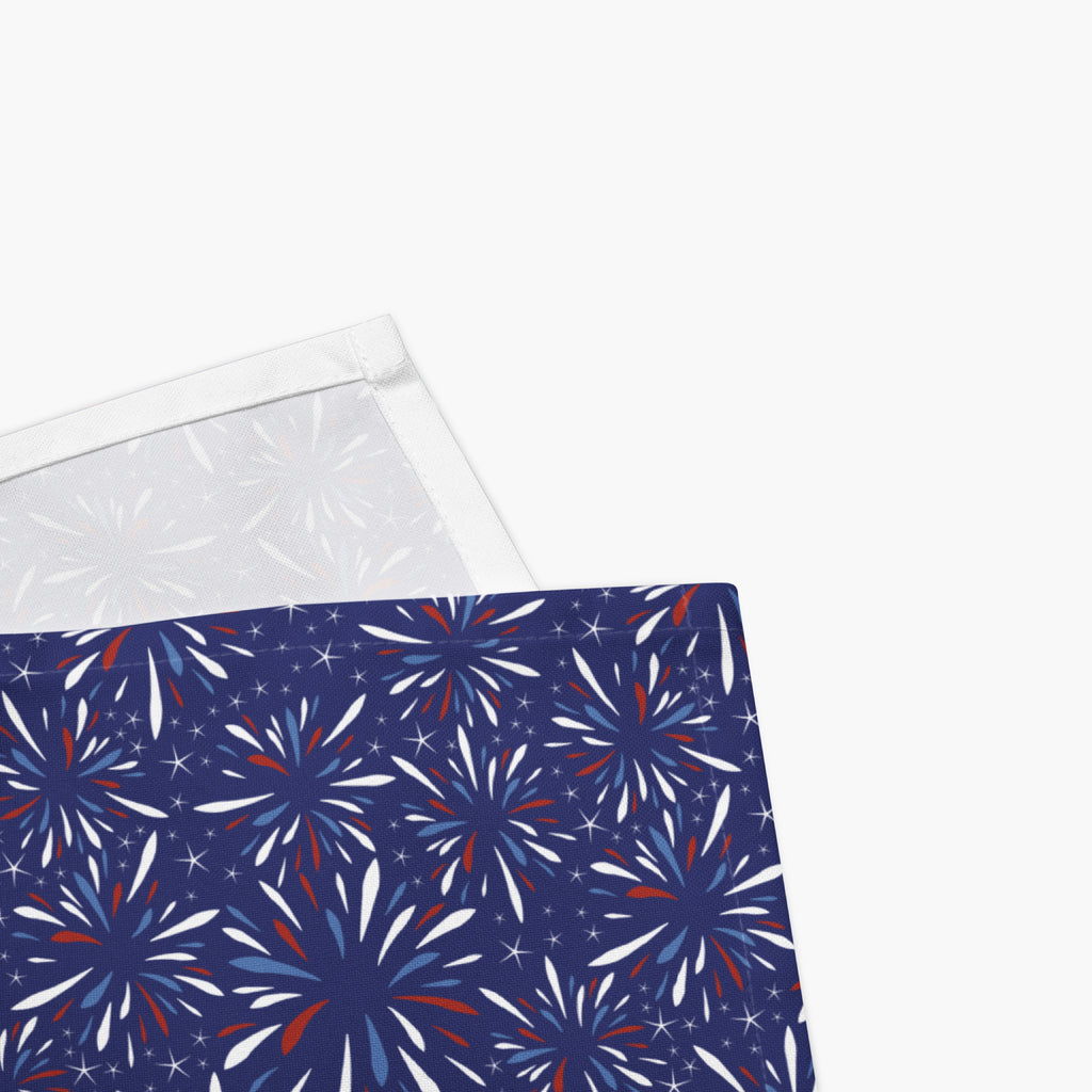 Close-up corned of cloth napkins with a colorful pattern of firework-themed illustrations on a white background.