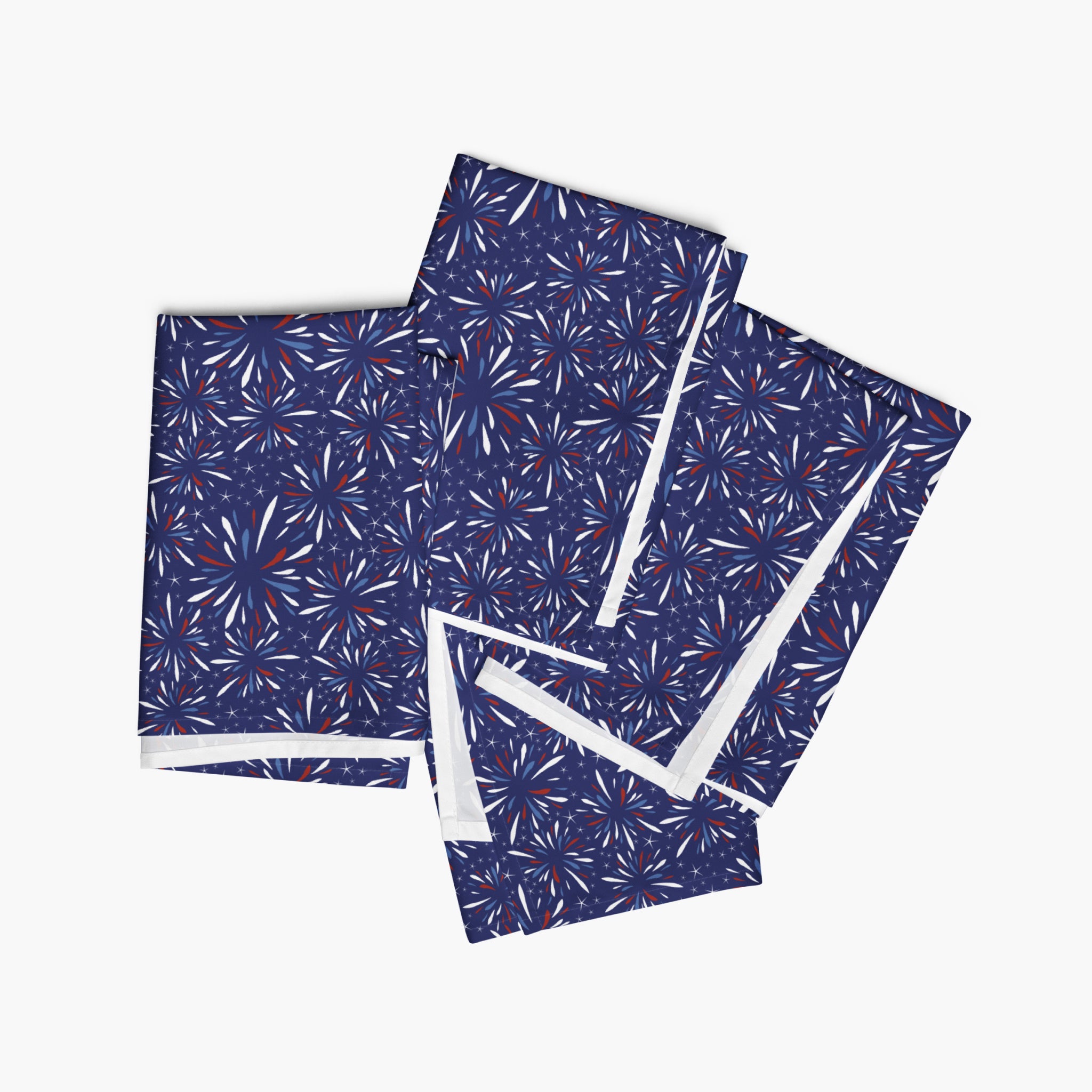 Four folded cloth napkins with a colorful pattern of firework-themed illustrations on a white background.