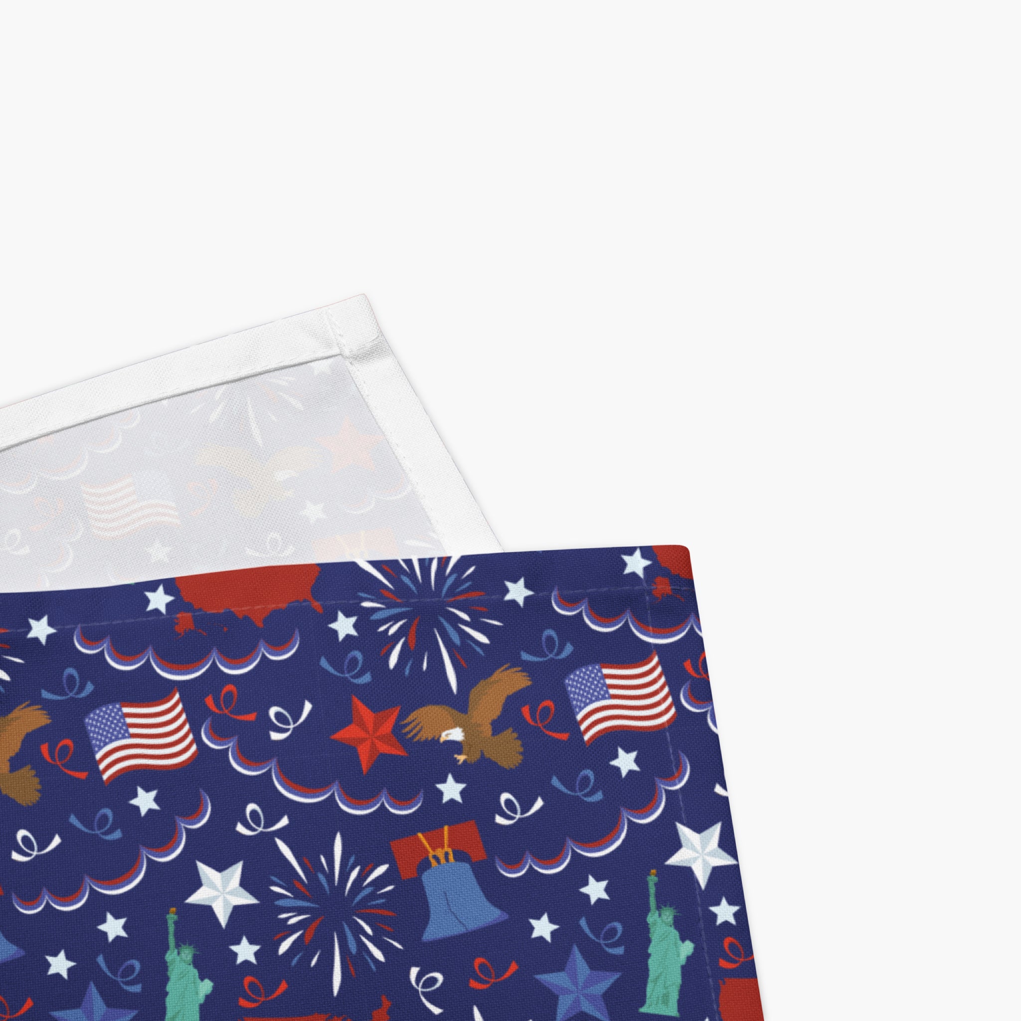 Close-up corned of cloth napkins with a colorful pattern of patriotic-symbol-themed illustrations on a white background.