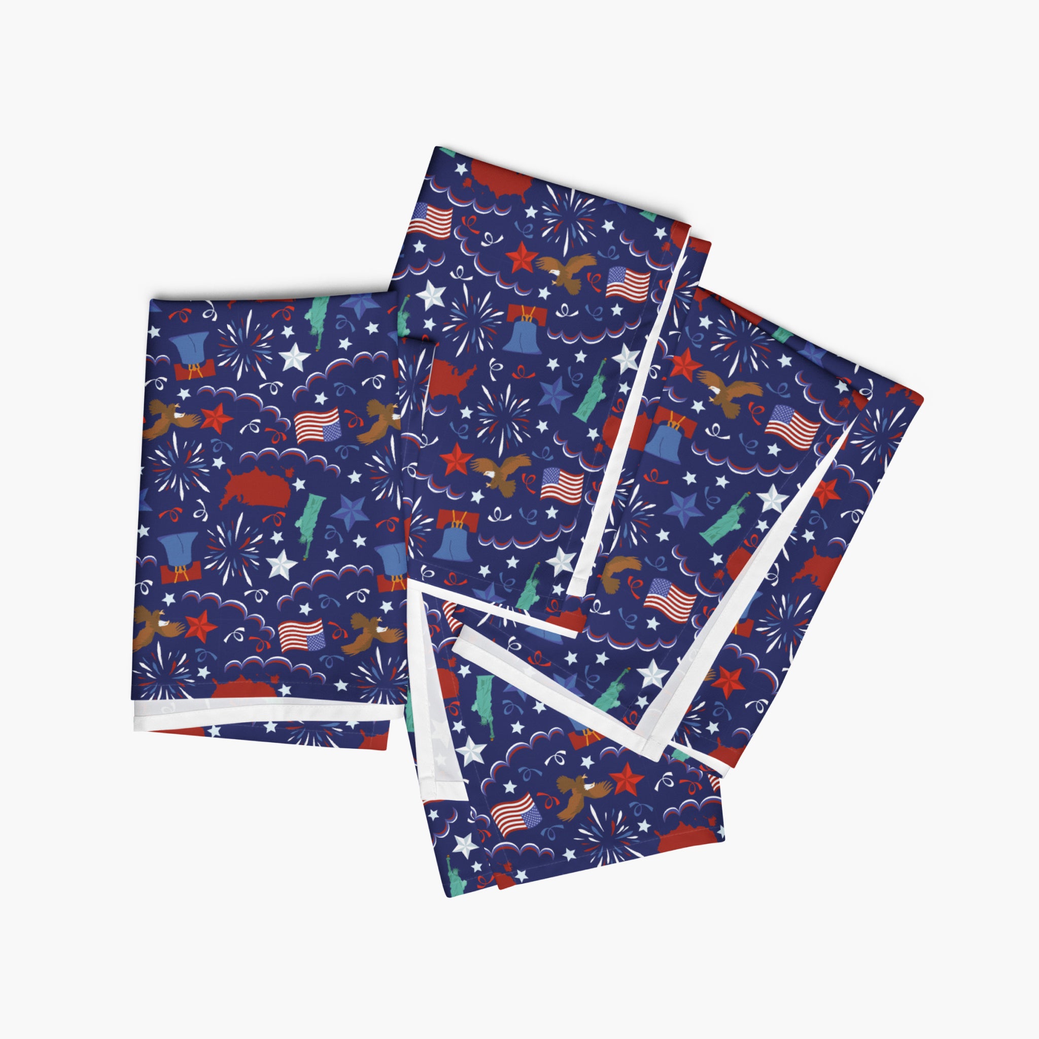 Four folded cloth napkins with a colorful pattern of patriotic-symbol-themed illustrations on a white background.