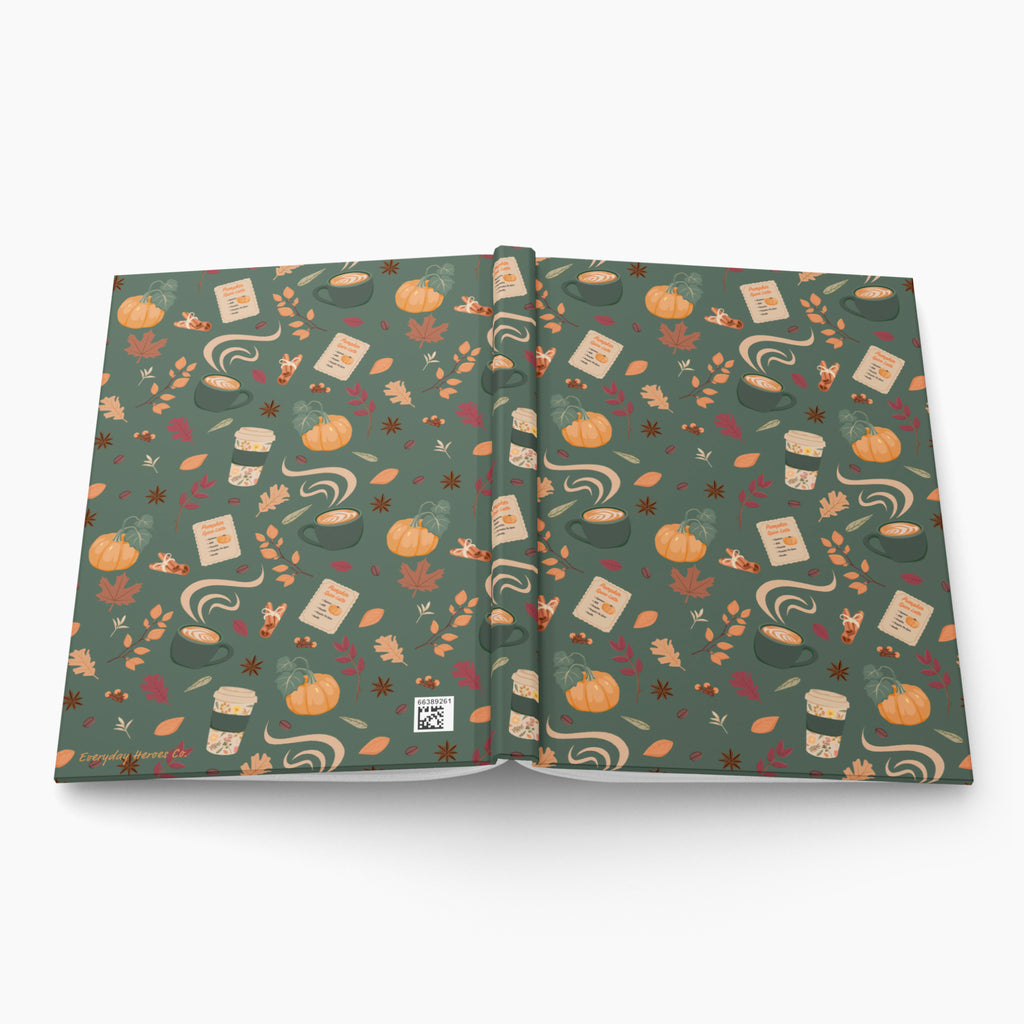 An open hardcover journal displayed flat against a light gray background. The cover features a cozy pumpkin spice pattern of coffee cups, leaves, recipe cards, fall motifs and pumpkins 