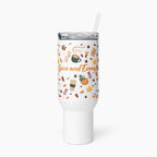 A white insulated tumbler with a clear lid and straw, featuring a pumpkin spice-themed print with autumn leaves, coffee cups, and the text 'Pumpkin Spice and Everything Nice' in orange script.