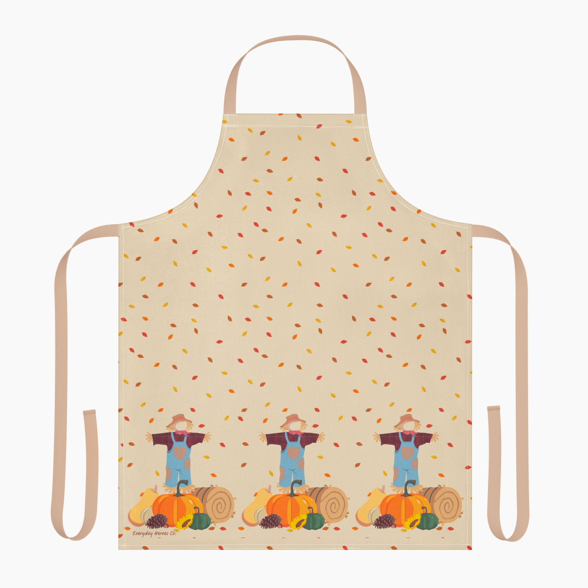 A beige apron with a light tan neck loop and side ties, decorated with a repeating pattern of scattered autumn leaves and three scarecrows standing next to pumpkins at the bottom.