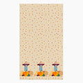 A rectangular beige kitchen towel, featuring an all-over autumn leaf print and a row of three scarecrows with pumpkins and gourds along the bottom edge.