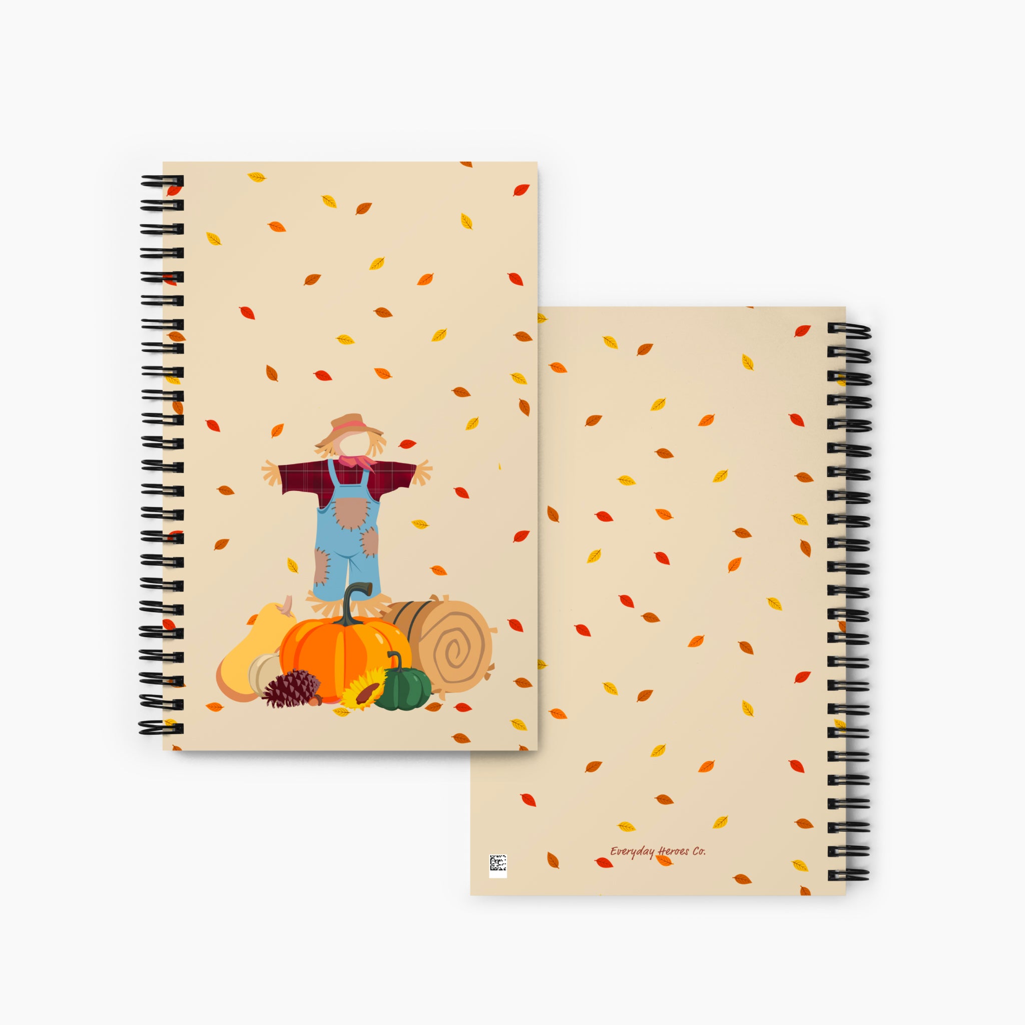 Front and back covers of a spiral-bound notebook with a beige cover featuring a cartoon scarecrow, pumpkins, gourds, and falling autumn leaves, shown on a light gray background.