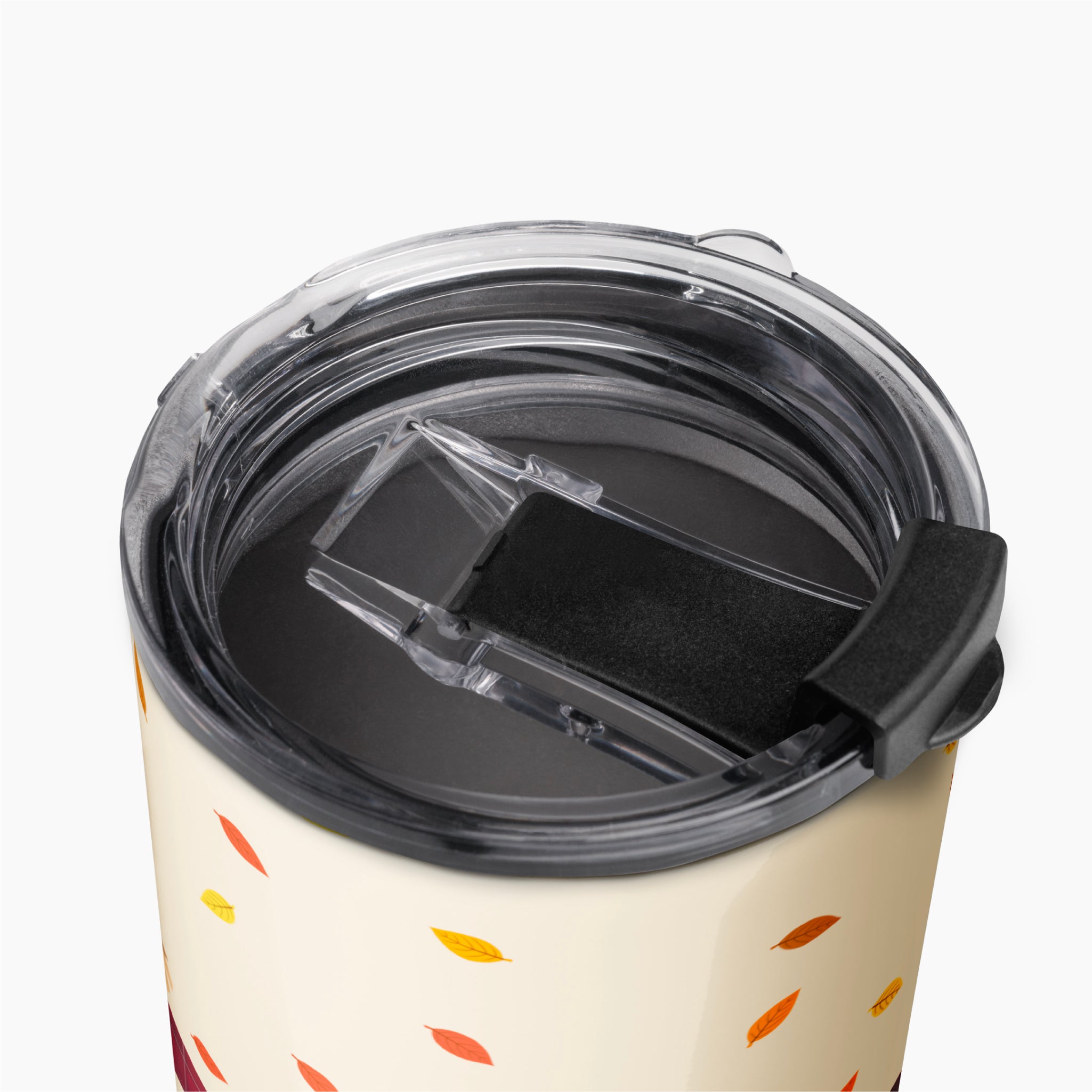 Close-up of a travel tumbler with a clear lid and black flip cover, decorated with a cream background and scattered autumn leaf patterns in orange, yellow, and red.