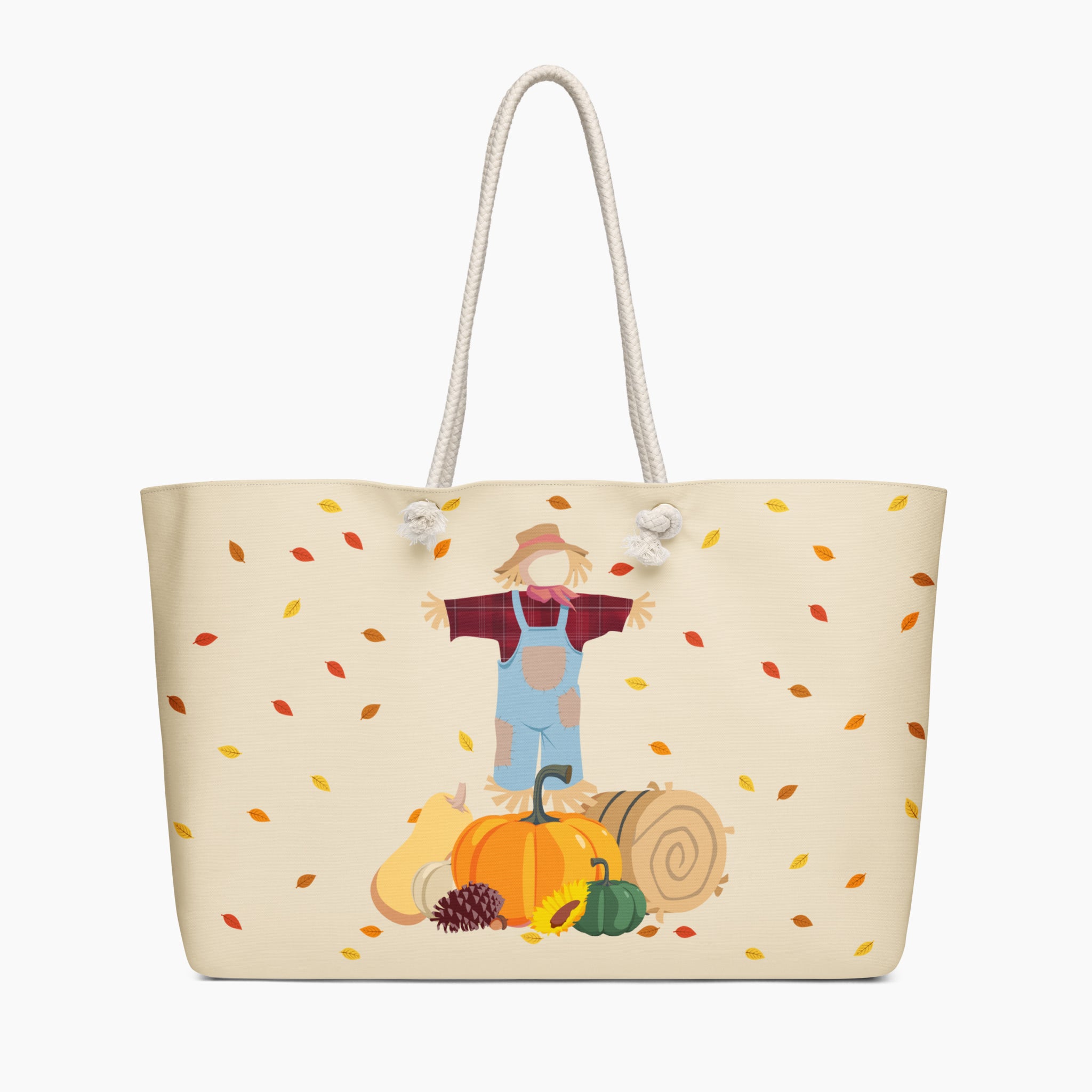 A cream-colored tote bag with white rope handles, featuring a printed autumn-themed illustration of a scarecrow standing behind a pumpkin with falling leaves. Staged on a light-grey background