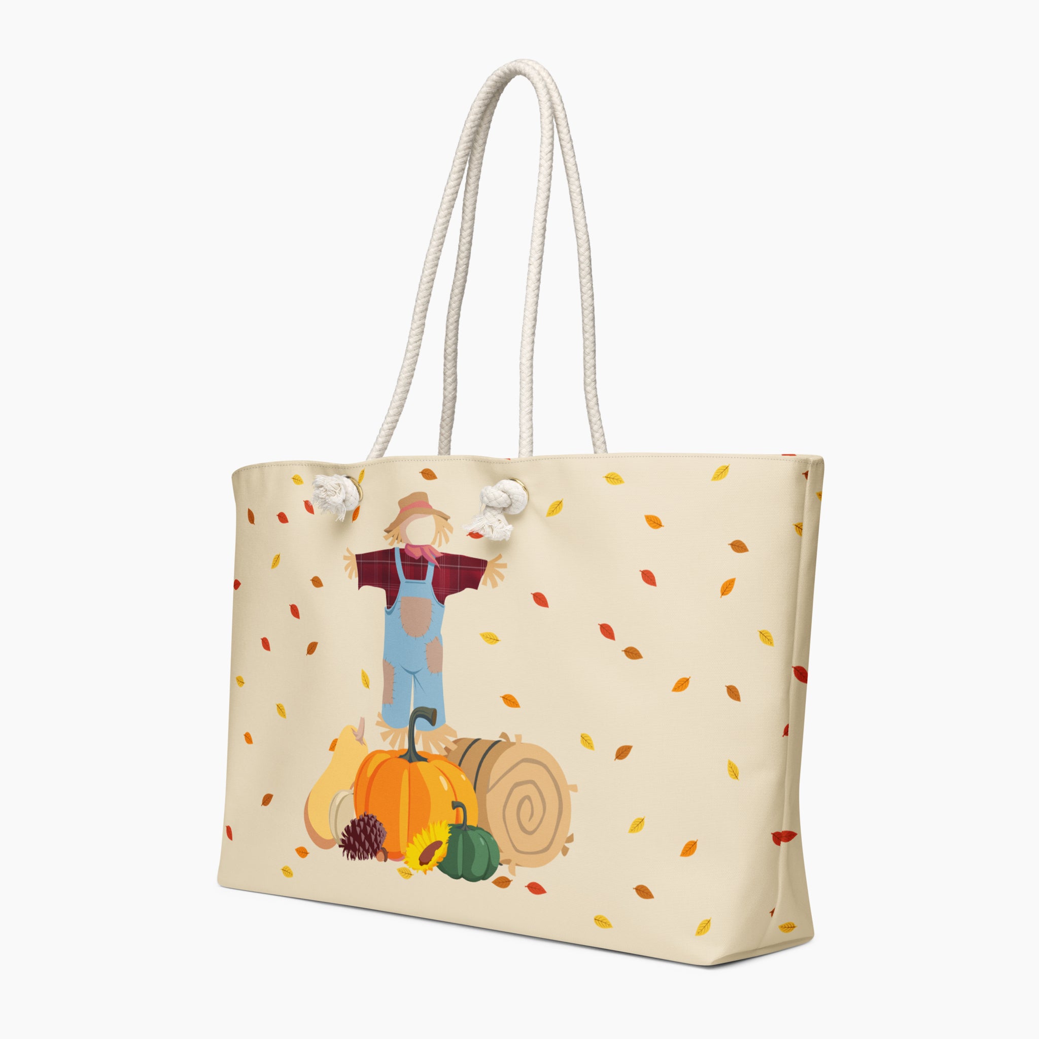 A cream-colored canvas tote bag with white rope handles, featuring a printed autumn harvest illustration of a scarecrow, pumpkins, and falling leaves.