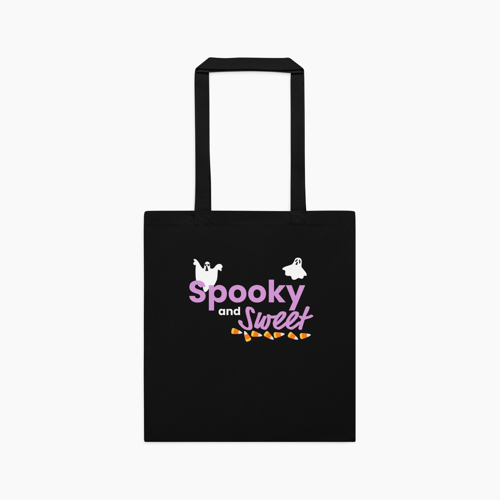 A black canvas tote bag with black handles, featuring a 'Spooky and Sweet' Halloween graphic in purple, white, and orange on the front, set against a plain light grey background.