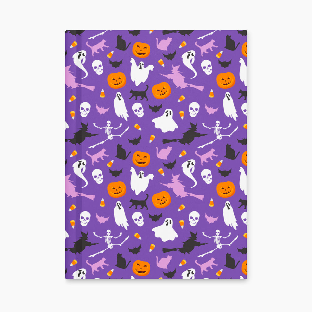 A notebook with a purple cover decorated with a Halloween pattern of ghosts, pumpkins, bats, and cats, shown flat upright against a light gray background.