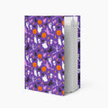 A notebook with a purple cover decorated with a Halloween pattern of ghosts, pumpkins, bats, and cats, shown standing upright against a light gray background.