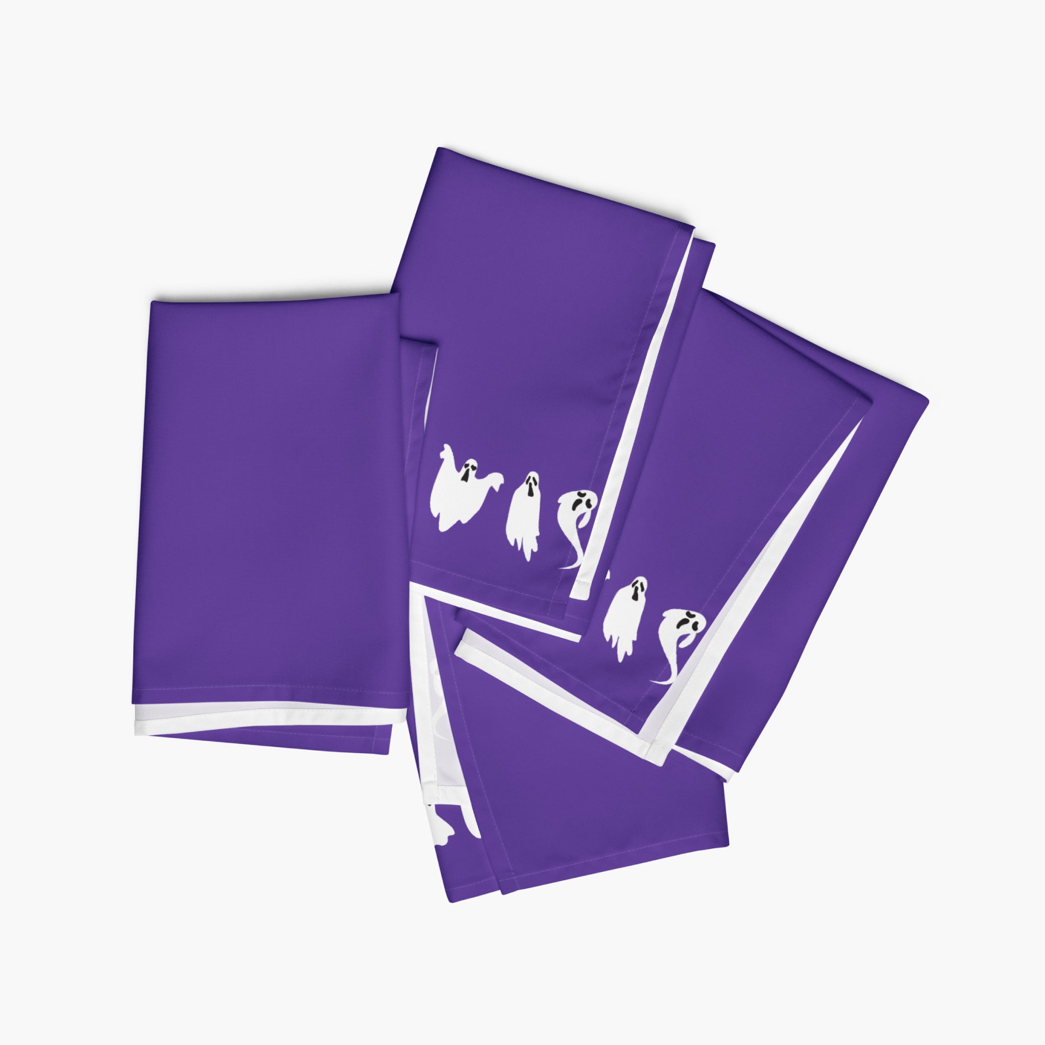 Four purple cloth napkins, featuring a white ghost pattern, arranged on a light gray background.