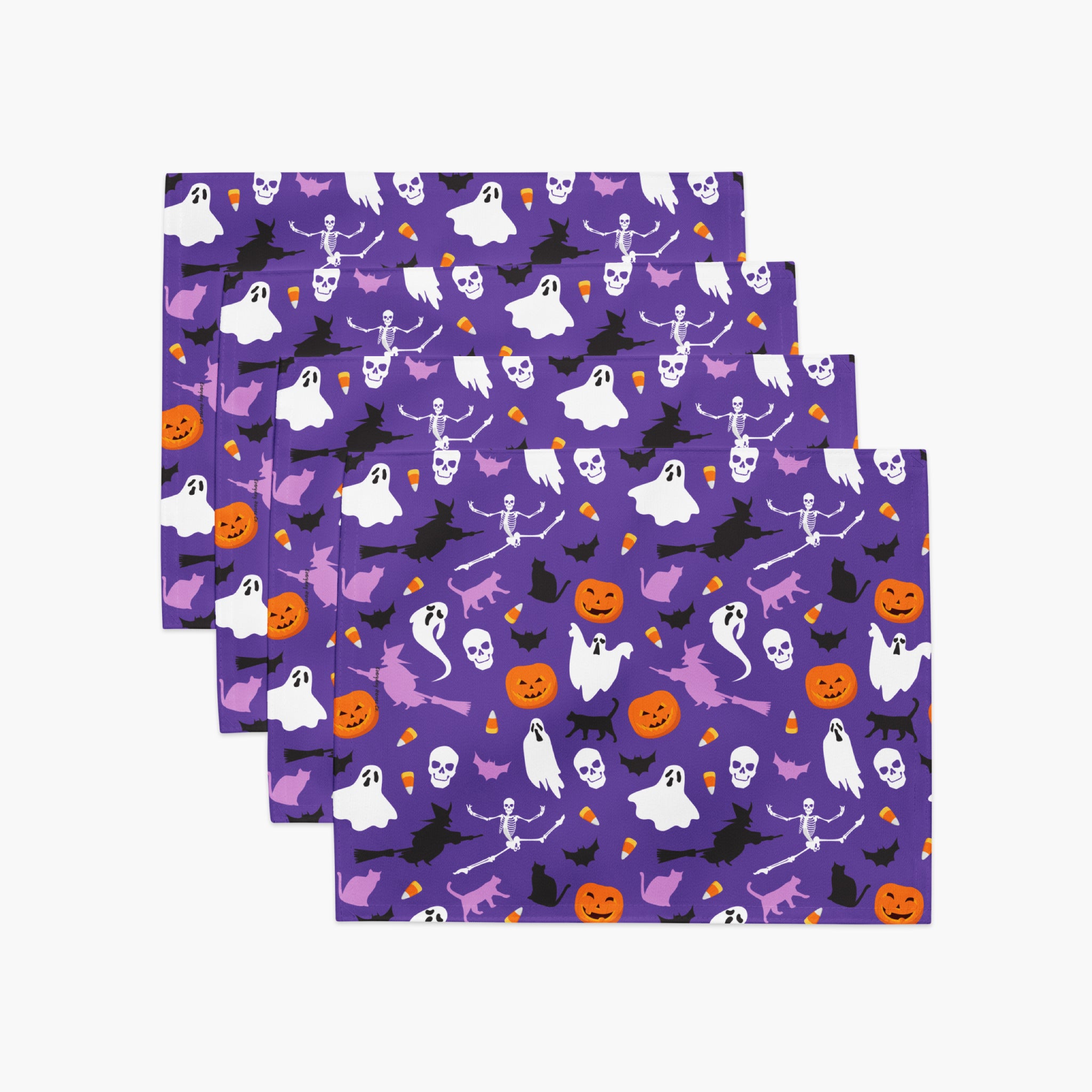 Four square cloth placemats with a purple Halloween pattern, stacked and fanned out on a light gray background. The pattern features white ghosts, black bats and skeletons, orange pumpkins, and small purple witches.