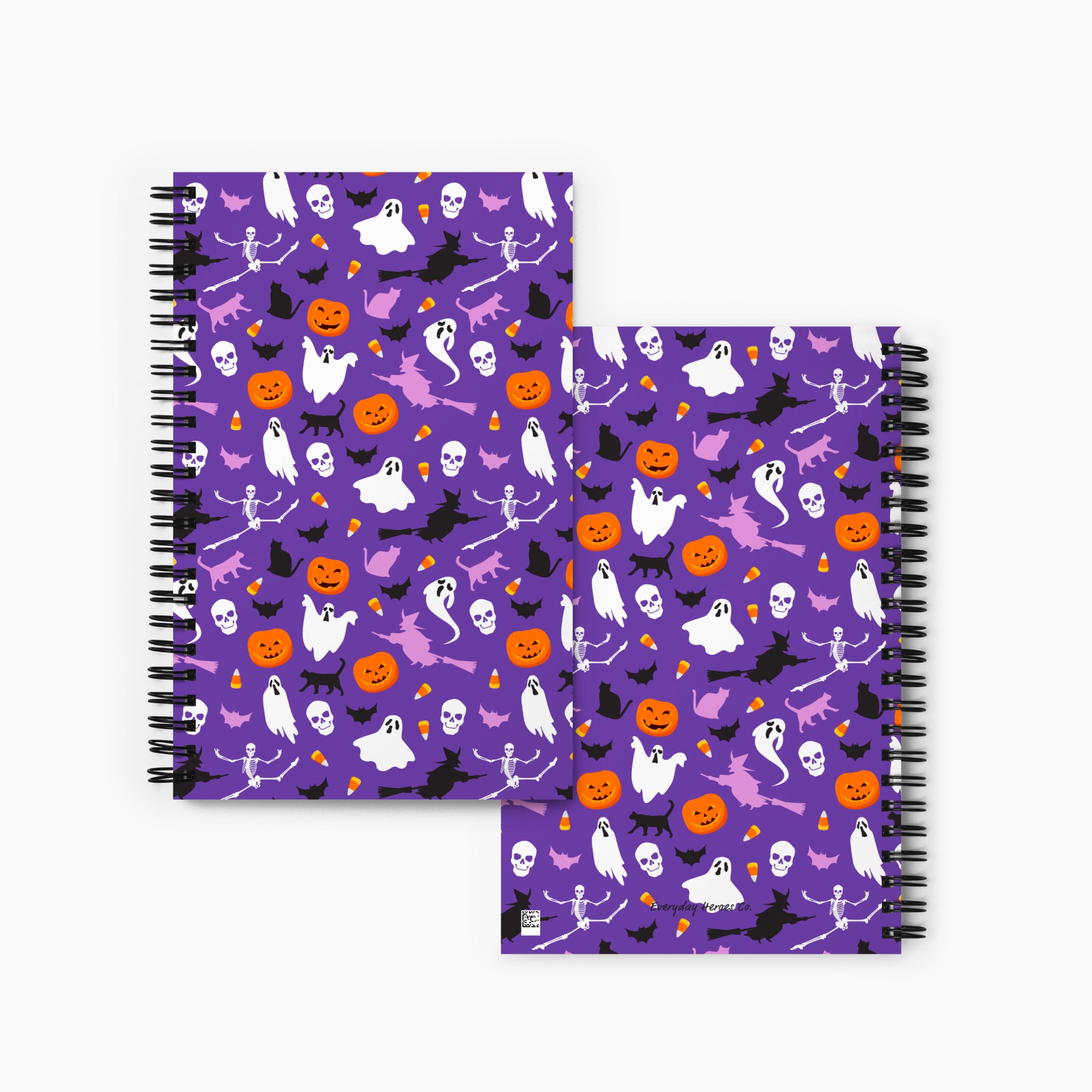 Front and back covers of a spiral notebook with purple covers featuring a Halloween pattern of ghosts, bats, skulls, pumpkins, and spiders, displayed on a light gray background.