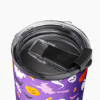 A close-up of a purple tumbler with a Halloween pattern of ghosts, pumpkins, bats, and witches, shown from above with a clear lid and black flip cover.