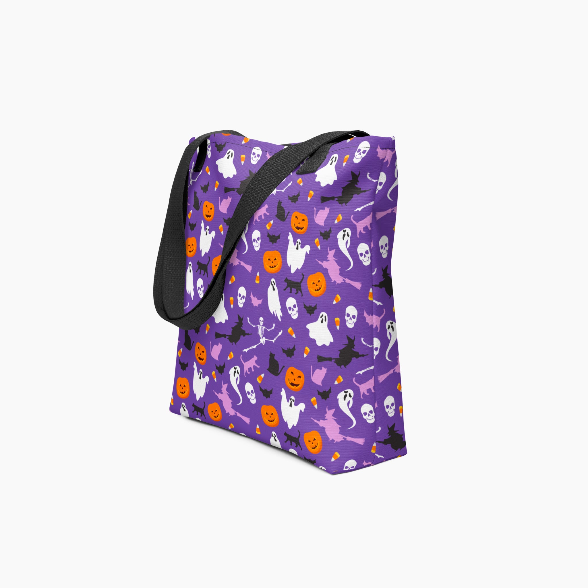A purple tote bag with a black handle, featuring a repeating Halloween pattern of white ghosts, orange pumpkins, black bats, witches and skulls on a light grey background.