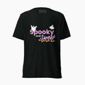 A black short-sleeve t-shirt with purple text that says 'Spooky and Sweet' with decorative halloween graphics, white ghosts and a bottom border on the text of candy corn. The shirt is staged on a plain light grey background.