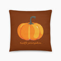 Square throw pillow with a orange pumpkin printed on a brown cover with the message "hello pumpkin" printed in script below. The pillow is staged on a light grey studio background.