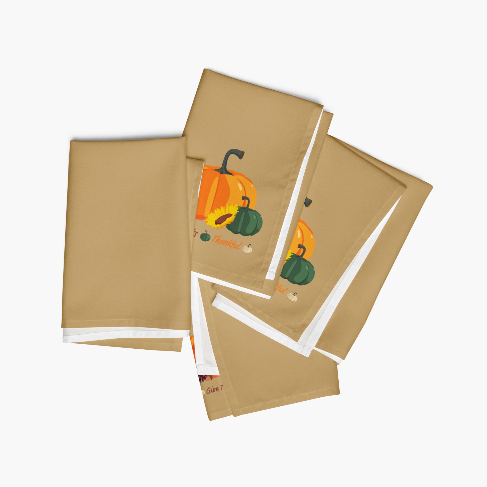 Four tan cloth napkins with a fall harvest illustration of orange and green pumpkins, arranged in a fan-like stack on a light grey background.