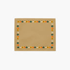 A cloth placemat with a decorative autumn border featuring pumpkins and sunflowers, sitting flat on a light grey background.