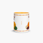 A white ceramic mug with a yellow interior, decorated with autumn-themed illustrations including pumpkins, and a pinecone, framed by a colorful leaf border. The mug is shown on a clean, light gray background.