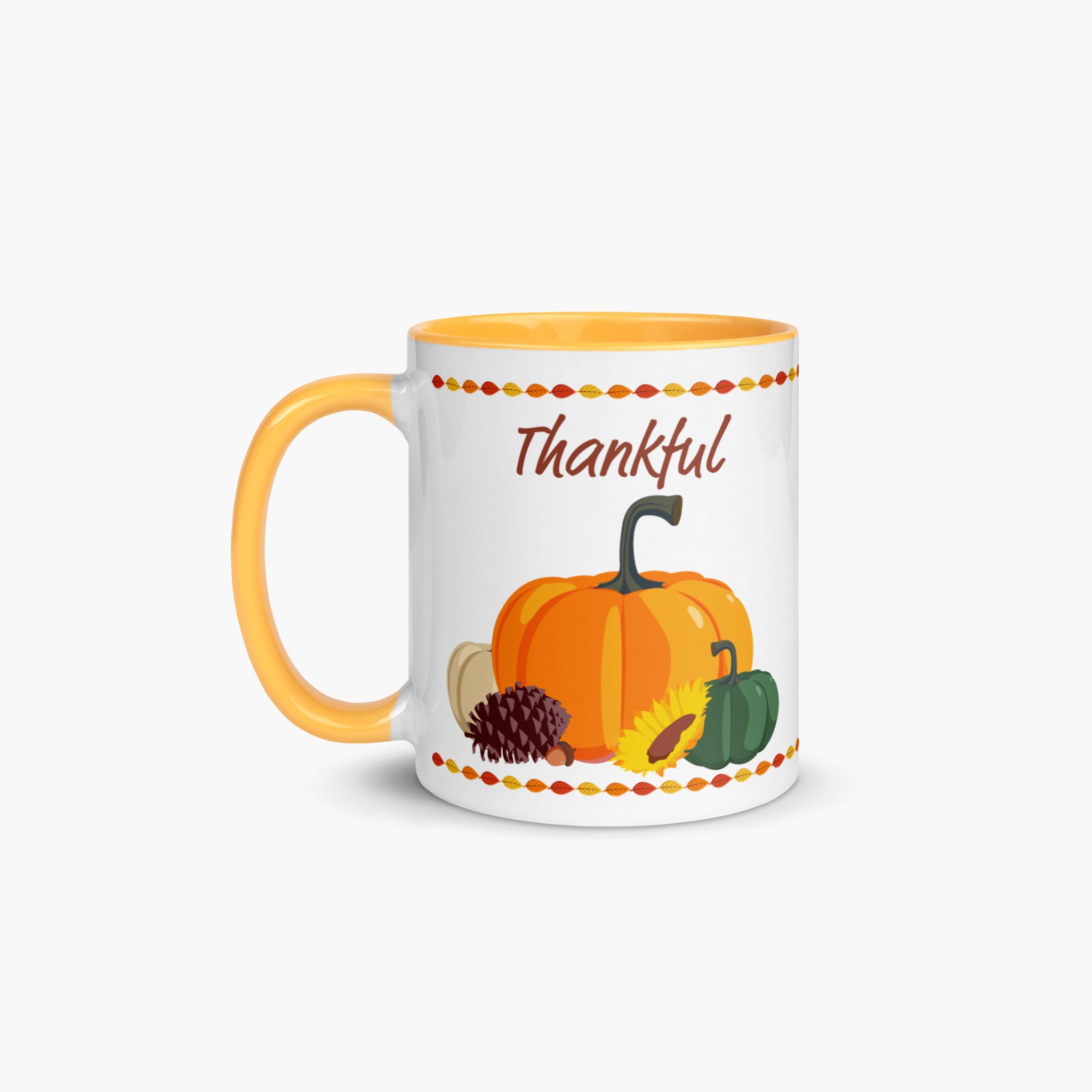 A white ceramic mug with a yellow handle and interior, decorated with an autumn harvest illustration featuring pumpkins, a pinecone, a sunflower, and the word 'Thankful' in brown script.