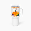 A white insulated travel tumbler with a clear lid and handle, featuring a fall harvest design with the word 'Thankful' above pumpkins, sunflower, and pinecones.