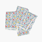 Four white floral-patterned cloth napkins stacked on a white background