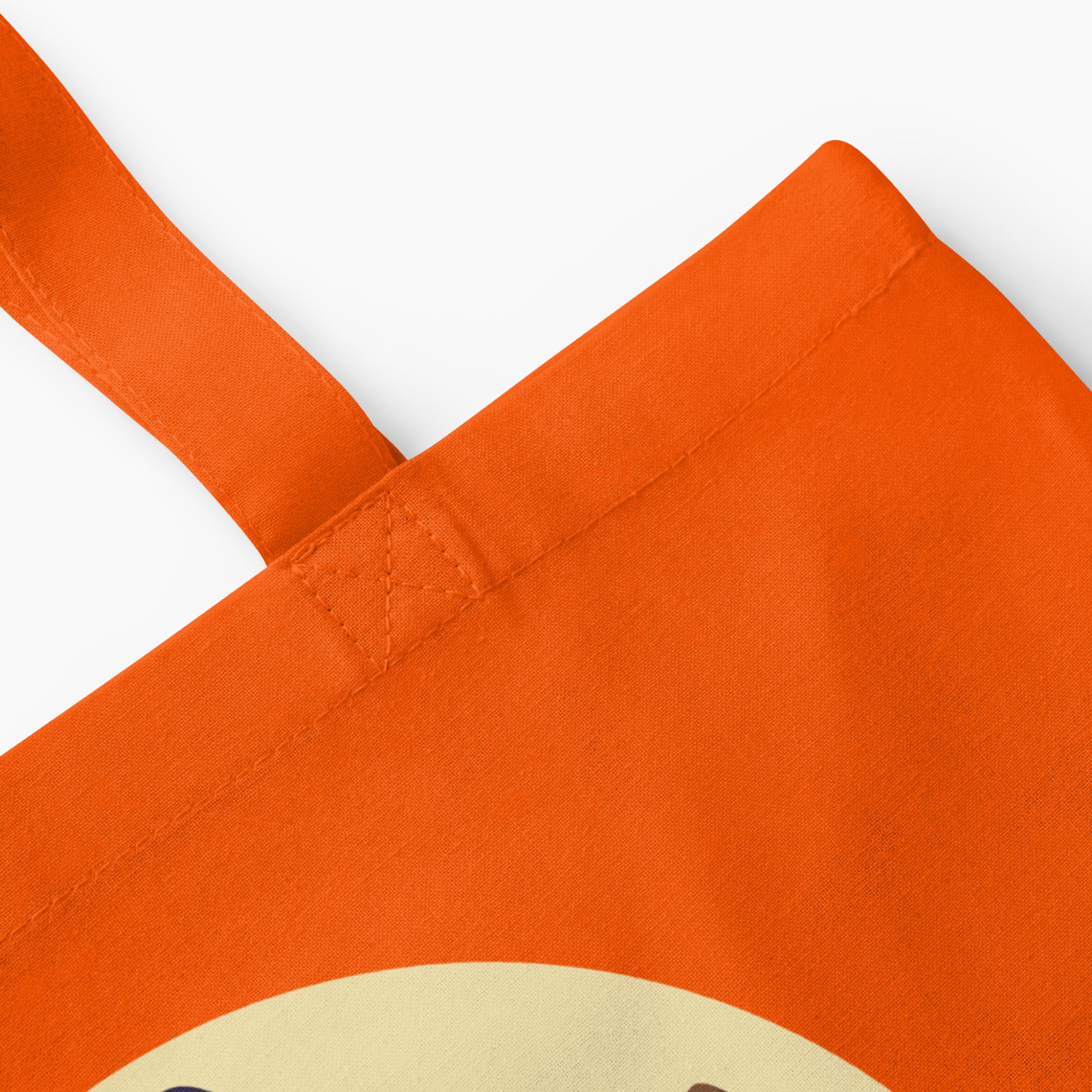 A closeup of an orange canvas tote bag with orange handles, featuring a 'Witch way to the Candy' message and cartoon girl dressed up as a witch on a broom, set against a plain light grey background.