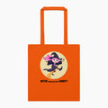 A orange canvas tote bag with orange handles, featuring a 'Witch way to the Candy' message and cartoon girl dressed up as a witch on a broom, set against a plain light grey background.